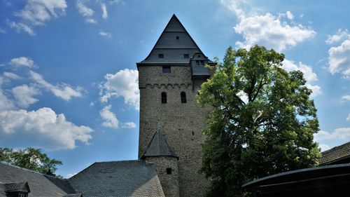 Low angle view of trees and building against sky