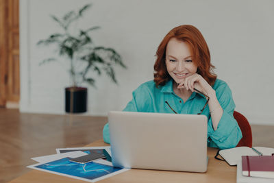 Portrait of young woman using laptop at home