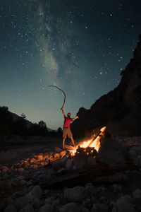 Man standing on rock against star field at night