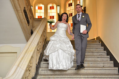Low angle view of falling bride holding man on steps