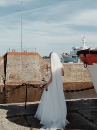 Woman standing on wooden post against sky