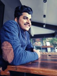 Portrait of smiling young man sitting on table