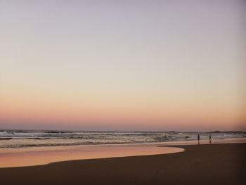 Scenic view of beach against clear sky during sunset