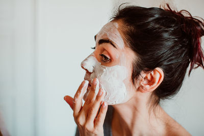 Close-up of woman applying facial mask