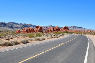 Road by desert against blue sky