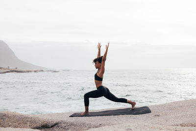 Full length of woman doing yoga at beach