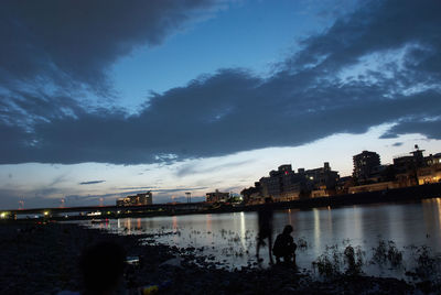 Silhouette people on illuminated city against sky at night