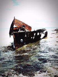 Abandoned boat on sea shore against sky