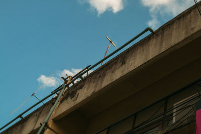Low angle view of bridge by building against sky