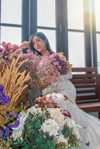 Portrait of bride sitting by flowers on bench