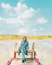 Portrait of smiling woman sitting against sky