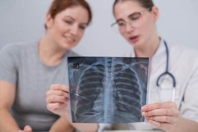 The doctor consults a caucasian woman and comments on the x-ray of the lungs