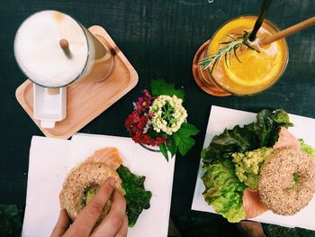 Sesame bagel filled with smoked salmon with avocado mash and green leafy salad 