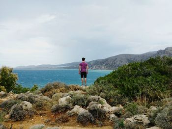 Woman standing on rock by sea