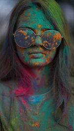 Portrait of woman standing being covered in coloured powder at holi festival.