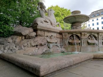 Statue by fountain against trees