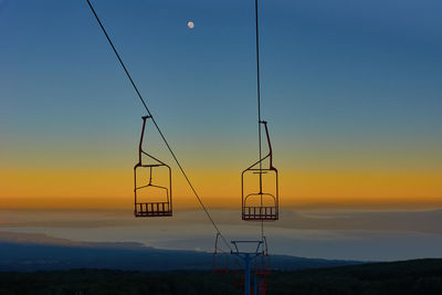 Silhouette cranes against orange sky