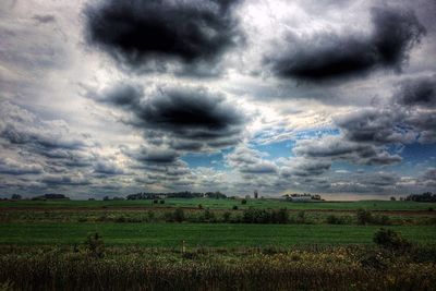 Scenic view of field against storm clouds