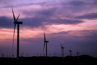 Low angle view of silhouette wind turbine against sky during sunset