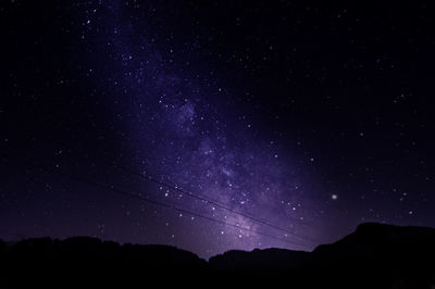 Low angle view of silhouette landscape against star field at night