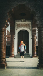 Rear view of woman walking against building