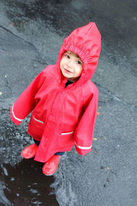 High angle portrait of smiling cute boy wearing red raincoat