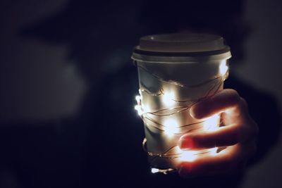 Close-up of hand holding illuminated candle