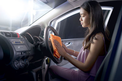 Young woman using mobile phone while sitting in car