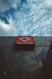 Low angle view of sign on wall against sky