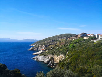 Scenic view of sea by buildings against blue sky