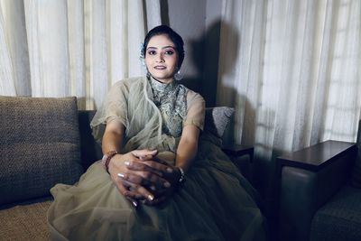 Portrait of smiling young woman sitting on sofa at home