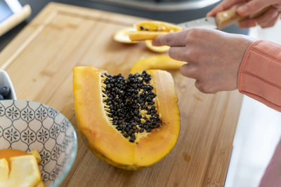 Woman cutting papaya in kitchen at home