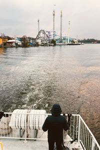 Man on a ferry looking at an amusement park.