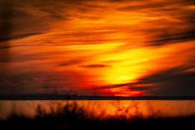 Scenic view of sea against dramatic sky during sunset