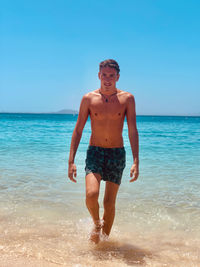 Portrait of shirtless man walking at beach