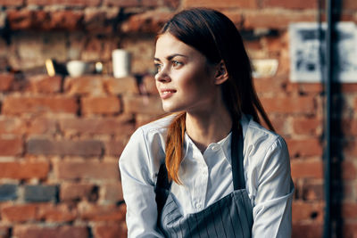 Portrait of a smiling young woman standing against wall