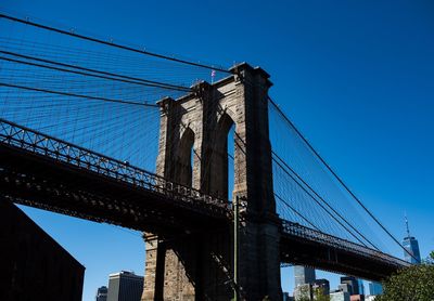 Low angle view of suspension bridge against blue sky