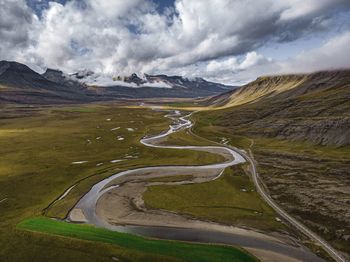 Scenic view of road by mountains against sky