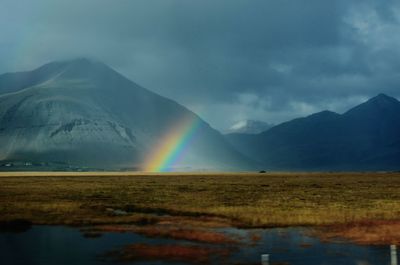 Scenic view of rainbow over mountains against sky