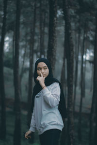 Full length of a young woman standing in forest