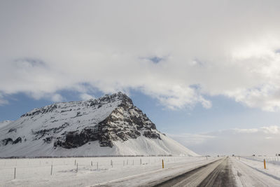 Road by snowcapped mountain against sky