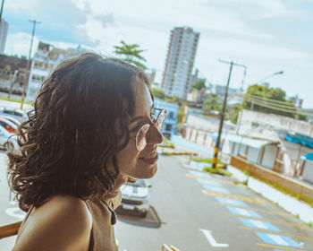 Side view of woman looking away while standing in city