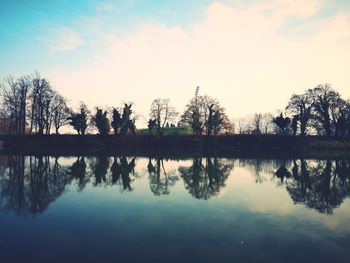 Reflection of silhouette trees in lake against sky during sunset