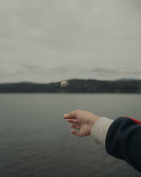 Midsection of person holding sea against sky