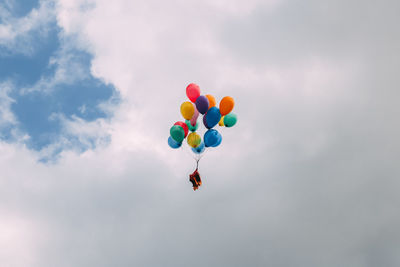 Low angle view of multi colored balloons flying against sky