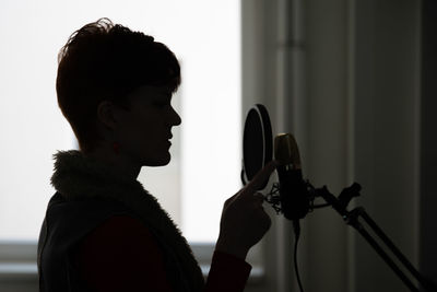 Side view of woman singing in studio