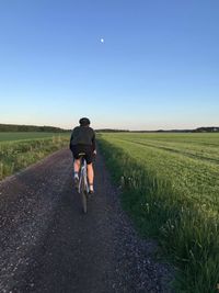 Rear view of man riding bicycle on road