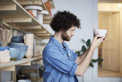 Side view of man looking at bowl in art studio