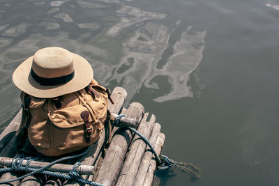 High angle view of bag and hat on wooden post by lake