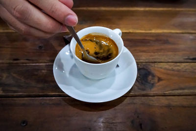 Close-up of hand holding coffee cup on table